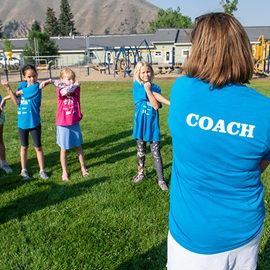 A Girls On The Run coach shows youth runners how to stretch. 